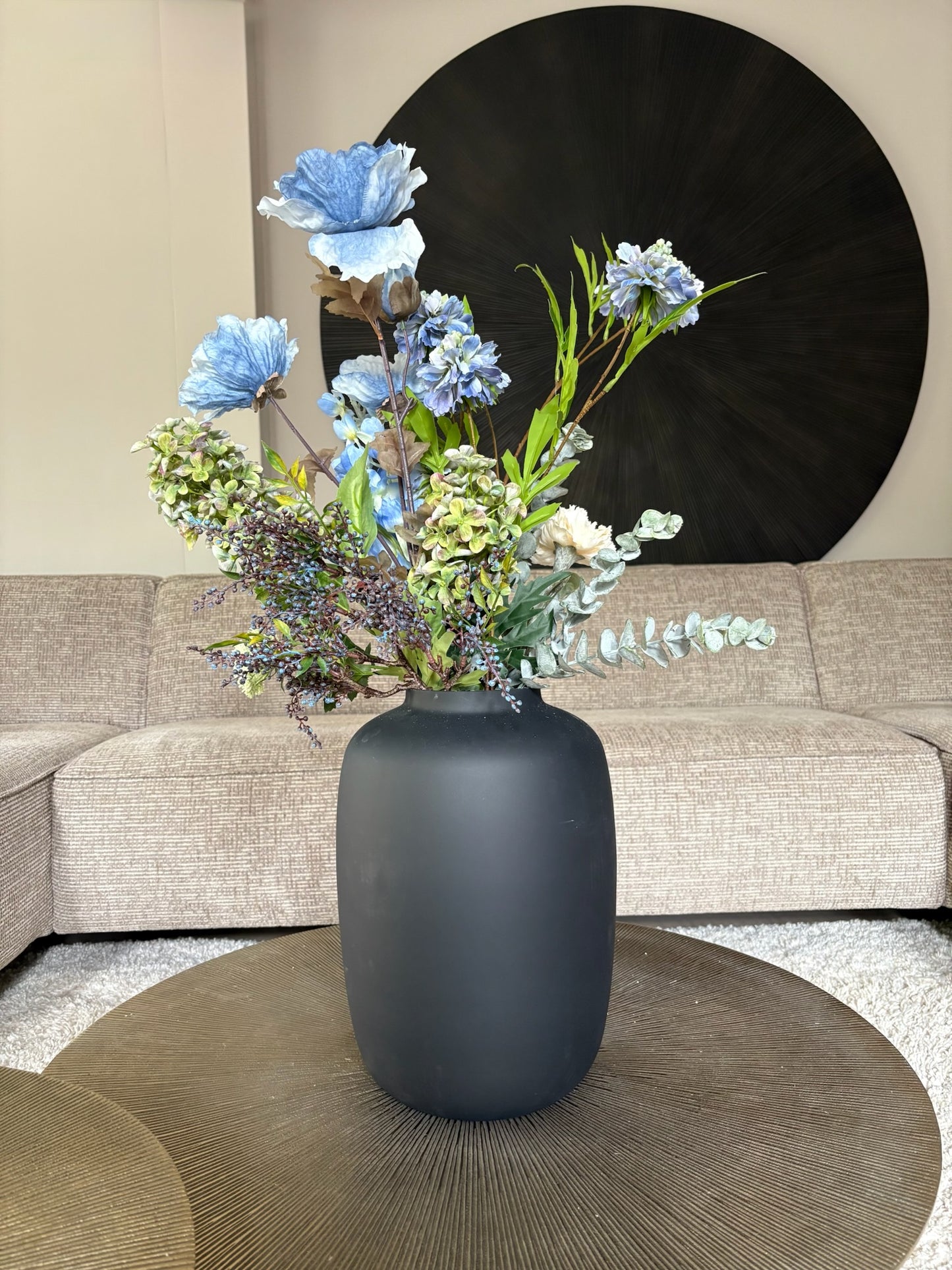 Zijden boeket Marin met een blauwe Poppy als blijkvanger in een zwarte vaas op een tafel