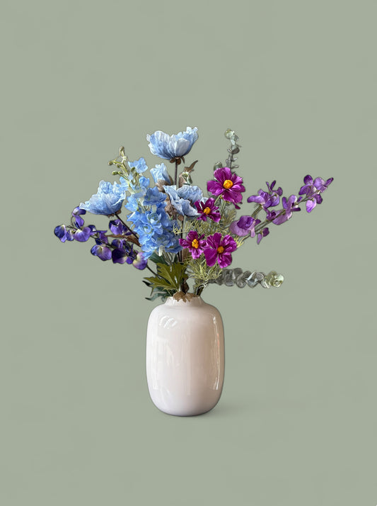 Zijden plukboeket Zara met een blauwe delphinium pioenroos en paarse cosmos in een ivoor kleurige vaas