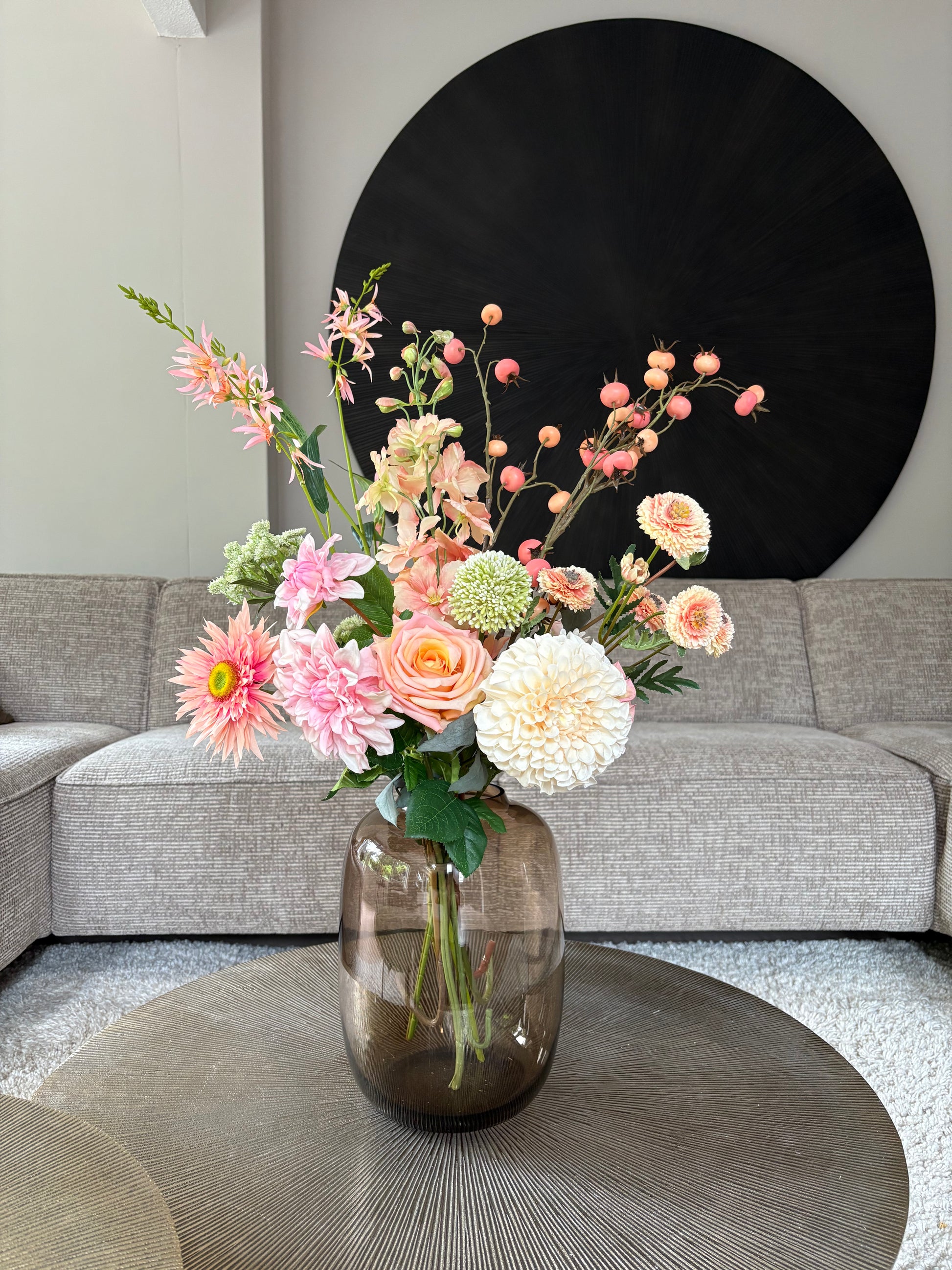 Zijden boeket Isa met abrikooskleurig bloemen in een taupe vaas op een tafel