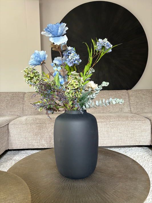 Zijden boeket Marin met een blauwe Poppy als blijkvanger in een zwarte vaas op een tafel