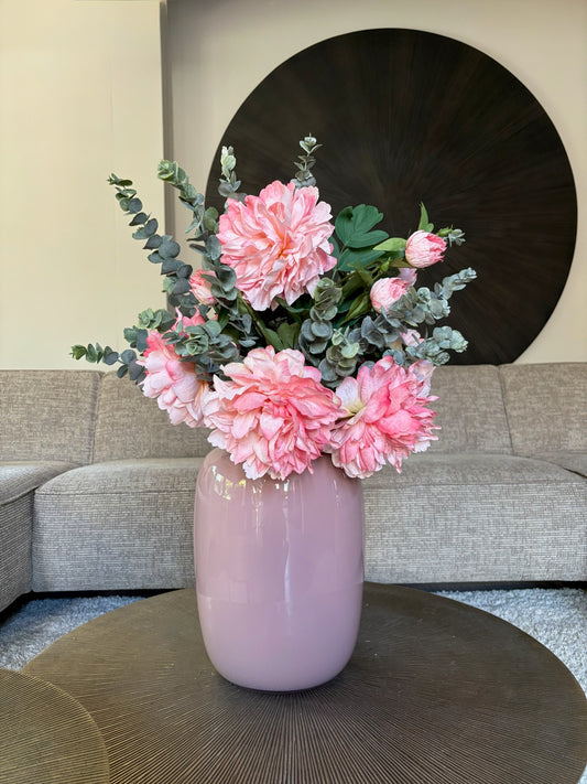 Zijden boeket met roze pioenrozen in een roze vaas op een tafel