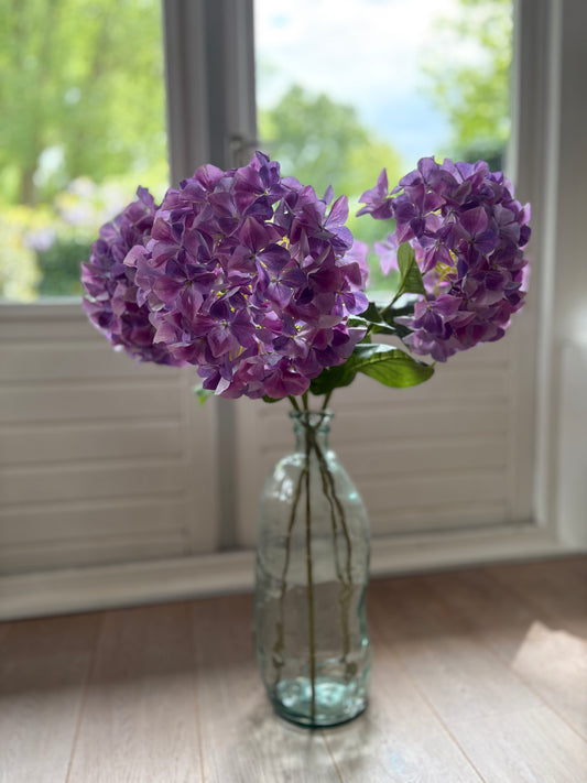 Zijden paarse hortensia in een glazen vaas