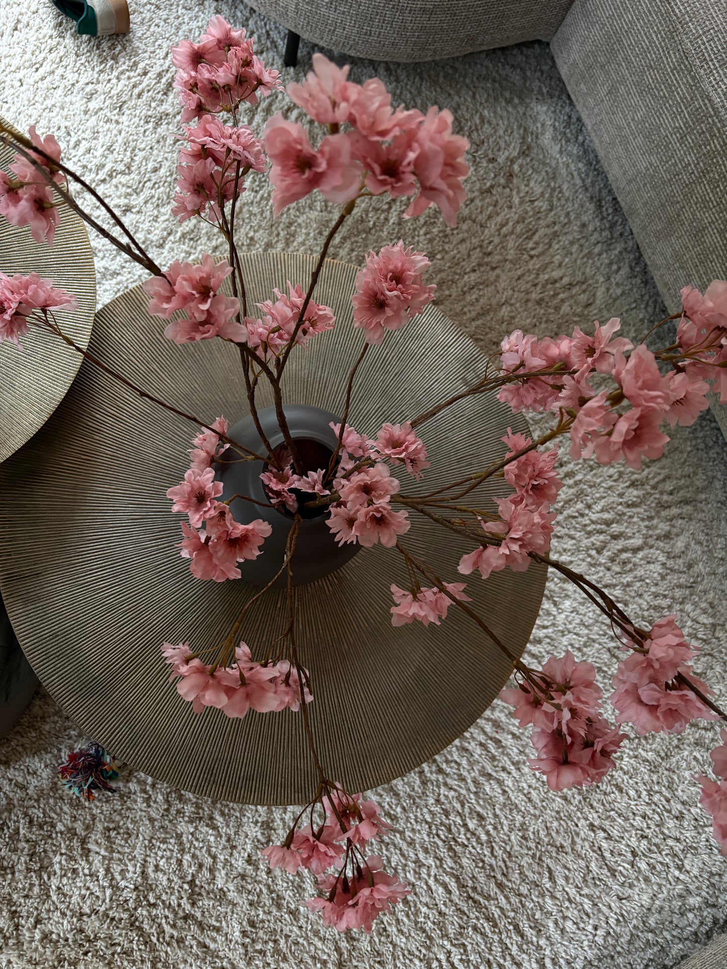 Close up: Zijden prunustak in taupe tint met verfijnde bloesems in een earth kleurige vaas van 29 cm hoog. Perfect als stijlvolle decoratie of aanvulling op een zijden boeket.