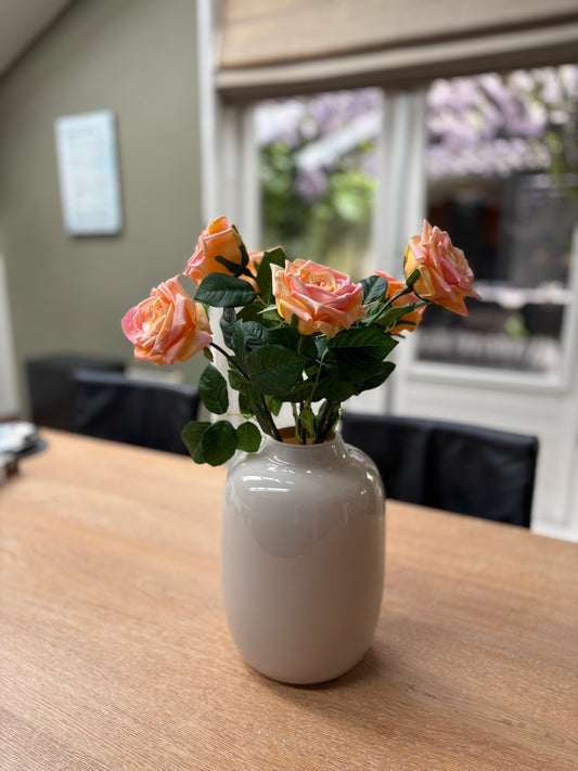 Zijden rozen perzikkleurig op een houten tafel