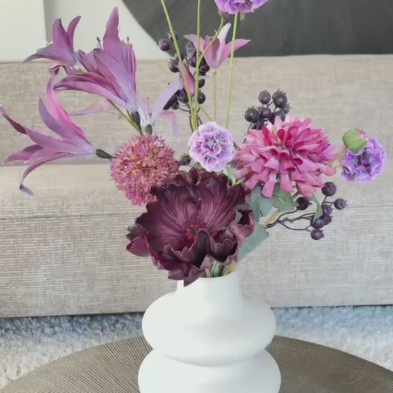 Video: Boeket Fee is een compact maar stijlvol zijden boeket met 6 paarse bloemen van hoogwaardige kwaliteit, waaronder een anemoon, scabiosa en dahlia. Een speels en elegant geheel.