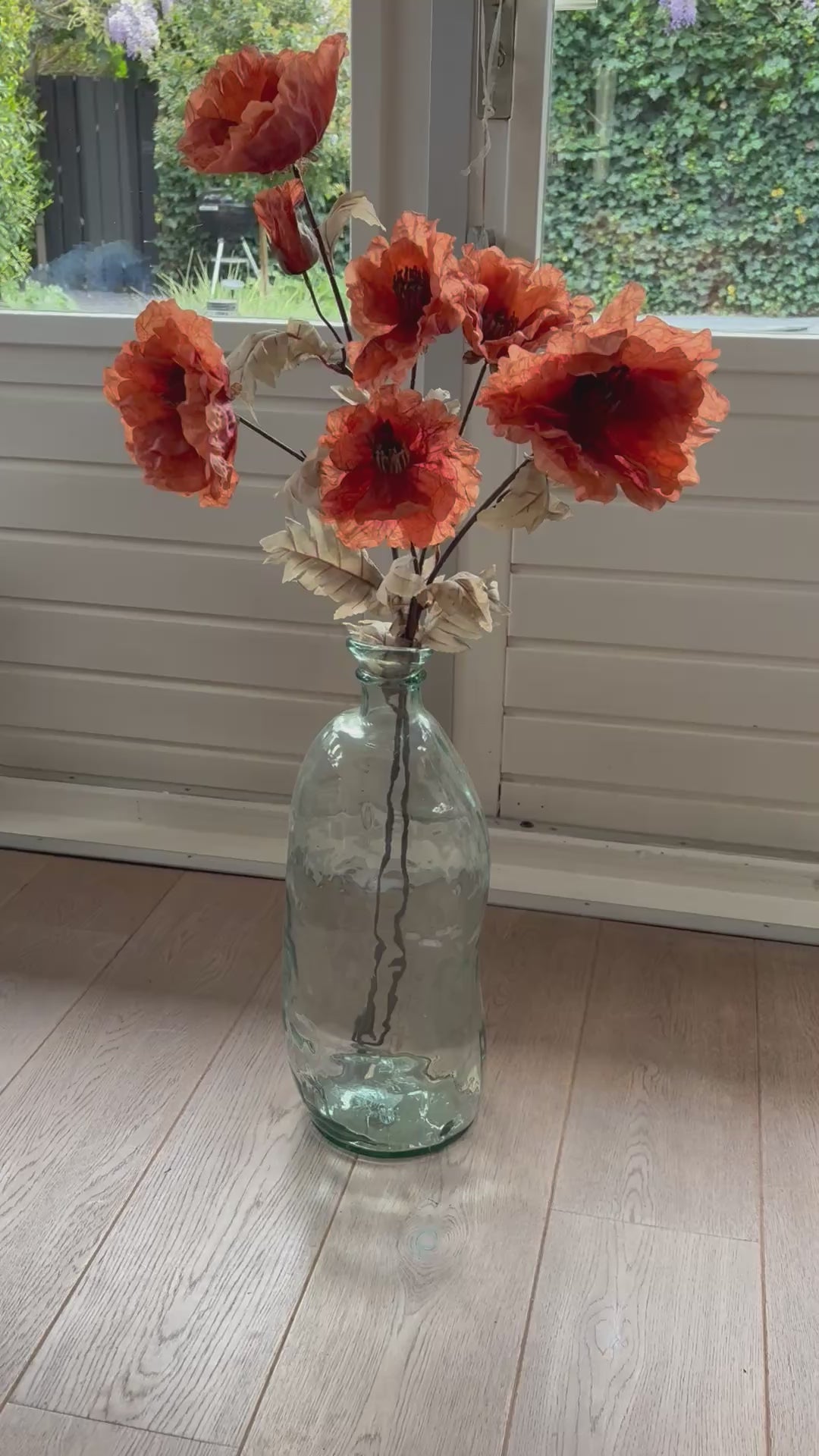 Video van zijden klaproos oranje in een glazen vaas